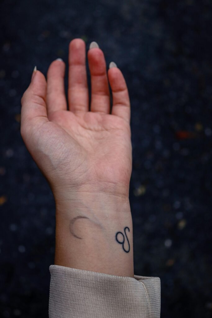 Close-up of a minimalist tattoo on an adult's wrist with outstretched hand.